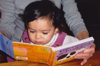 bebe regardant livre dans bras adulte